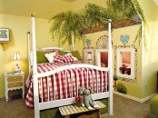 a bold kid’s room with yellow walls and a ceiling, painted greenery and mosaics on the walls, a white bed and red and white bedding, some art and a table lamp