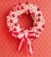 a candy cane wreath with red ornaments and an oversized ribbon bow is a lovely and chic idea of a Christmas decoration for outdoors or indoors