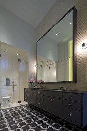an oversized mirror that takes a whole wall and that show off some hidden storage space inside is a bold and edgy solution for a modern bathroom