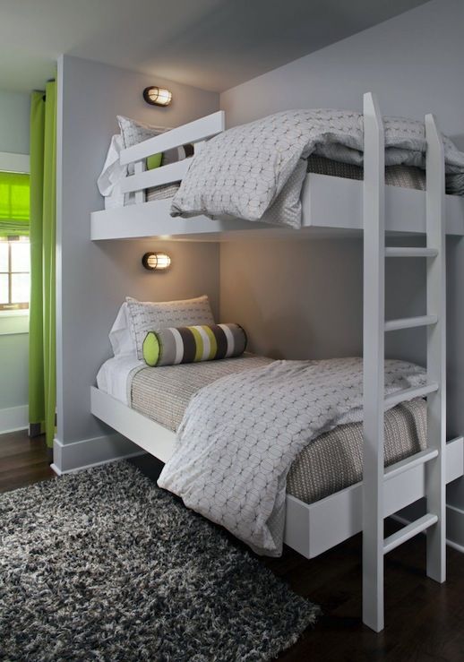 a contemporary white bunk bed set with a white ladder, small wall lamps and striped touches