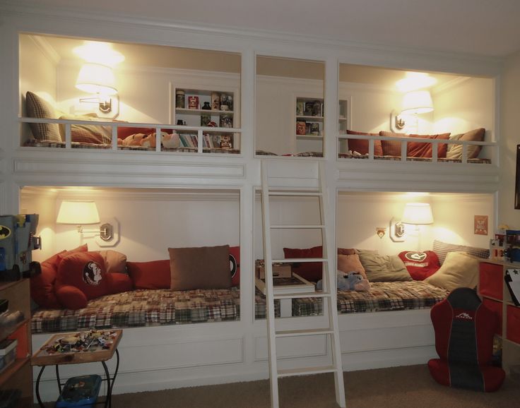A white vintage bunk bed set of four, cozy wall lamps and a single ladder plus built in shelves over each upper bed