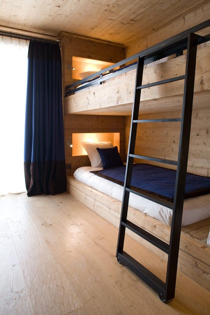 A wood clad bunk bed setup with built in lights and wiht a metal ladder looks veyr contemporary and inviting