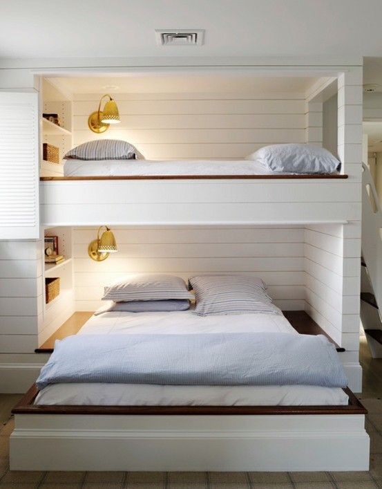 A unique bunk bed unit for two with a retractable bed in the lower part, wall sconces and built in shelves over the beds