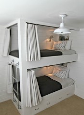 a contemporary bunk bed unit with a metal ladder attached and drawers integrated into the lower bed for storage and curtains for privacy