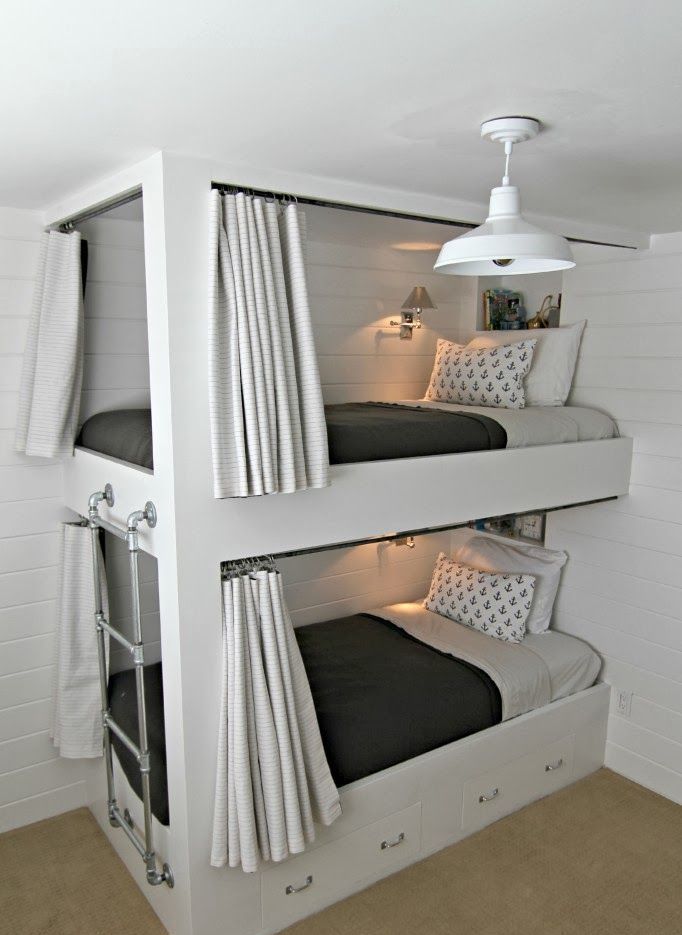 A contemporary bunk bed unit with a metal ladder attached and drawers integrated into the lower bed for storage and curtains for privacy