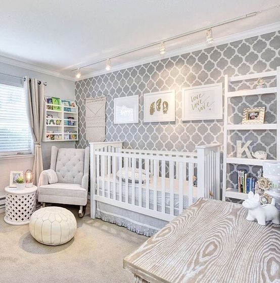 a gender neutral nursery with an accent wallpaper wall, white furniture, lights and white and neutral toys