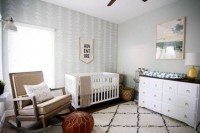 a neutral mid-century modern nursery with elegant furniture, a leather ottoman, signs and artworks is a very cozy and welcoming space