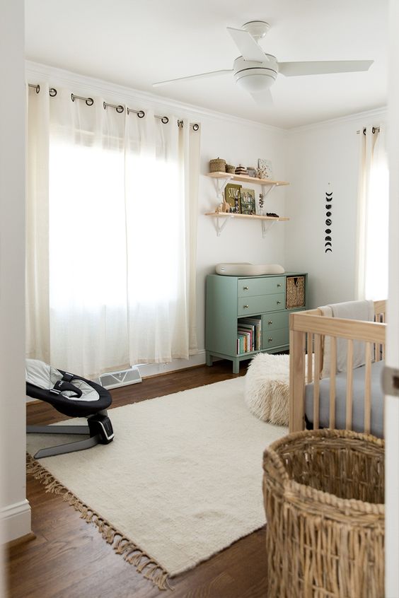 A neutral farmhouse nursery with light colored furniture, a green changing table, neutral textiles is a very cozy and welcoming room