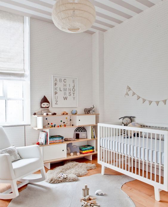 a mid-century modern gender neutral nursery with white and neutral furniture, with neutral textiles and colorful toys and books plus garlands