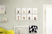 a gender neutral nursery in grey and white with bold yellow touches, with a printed wall, a gallery wall, a bold modern chandelier and a chair