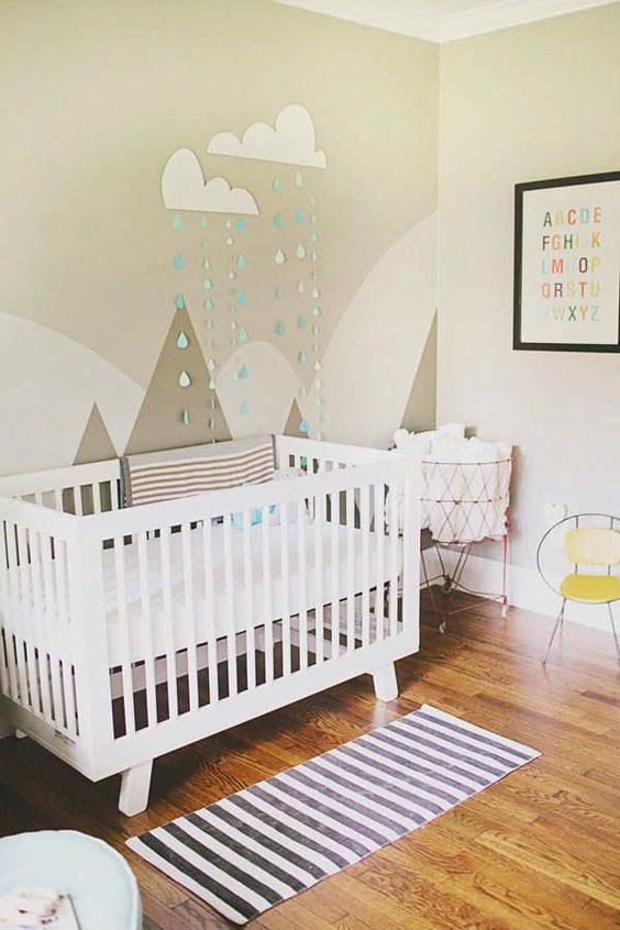 a gender neutral nursery with color block walls and mountains on the wall, a white crib and bright touches is a cozy room