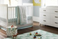 a gender neutral nursery with blue walls, chic white furniture, printed and colorful textiles and garlands, bright artworks