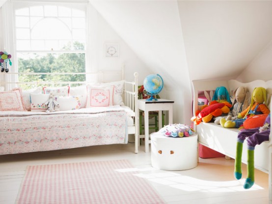 a neutral attic girl's room with white daybeds, floral print blankets and pillows, bold toys, and a box with toys is a lovely and welcoming space