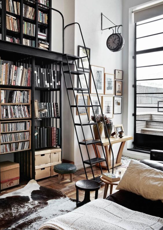 The steel bookcase with ladder is both functional and a signature piece; the Victorian clock underlines the “public space” feel