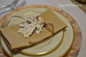 gold rimmed plates, gold napkins, leaves and a charger will add a warm and shiny glow to your fall tablescape
