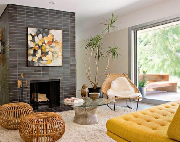 A welcoming mid century modern living room with a brick clad fireplace, a mustard sofa, wooden coffee tables and a white chair, a glass wall for natural light