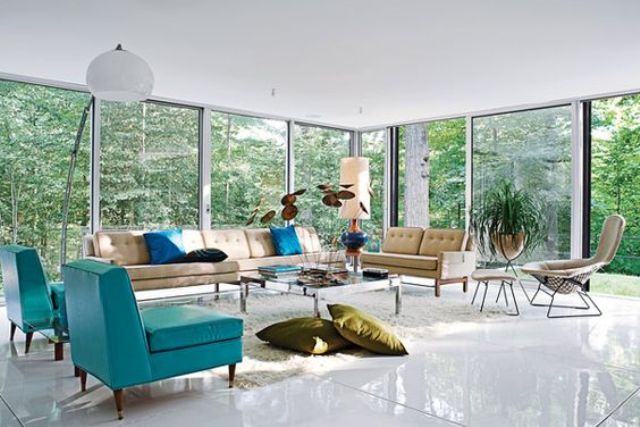 A mid century modern living room with glazed walls, tan and turquoise seating furniture, a low coffee table and pillows and lamps