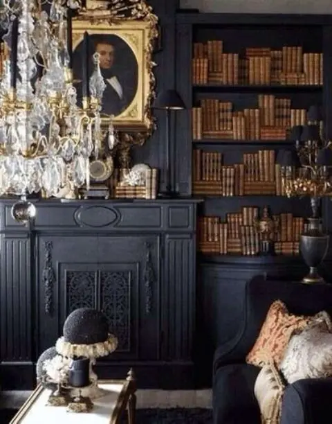A refined Gothic library in black, with built in shelves, a faux fireplace, a crystal chandelier, refined artworks and a low table plus a black sofa