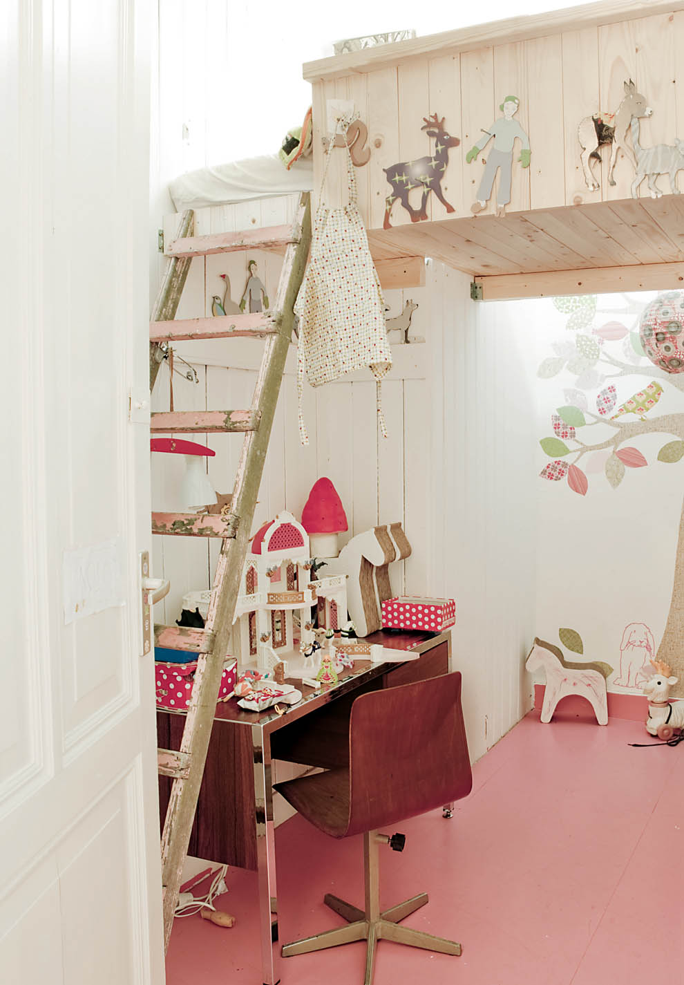 A Scandi meets shabby chic girl's room with a raised bed with a ladder, a stained desk and a chair, lights and fun wooden toys