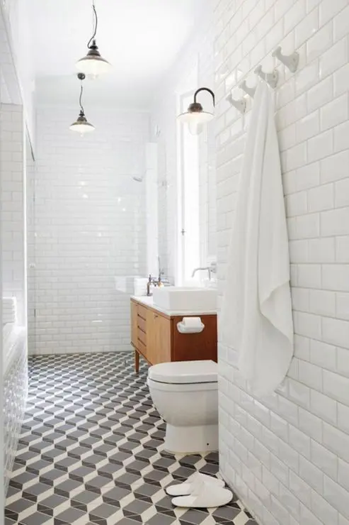 A mid century modern bathroom with white subway tiles on the walls and black and white geometric tiles on the floor is stylish and cool