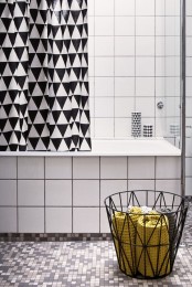 a geometric black and white shower curtain and a geometric wire basket with towels are stylish additions to any neutral bathroom