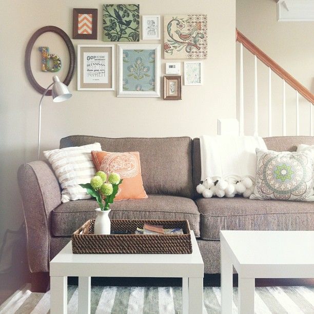 A neutral modern farmhouse living room with a taupe sofa and neutral pillows, a small vintage gallery wall and a couple of IKEA Lack tables plus a striped rug