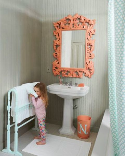 a cute grey and coral bathroom with an ornate mirror, a mint colored stand and a mint curtain