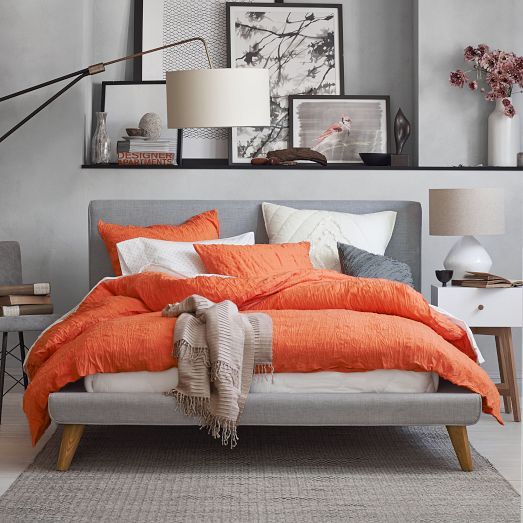 a contemporary bedroom with dove and darker grey walls, furniture and accessories and grey, white and coral bedding