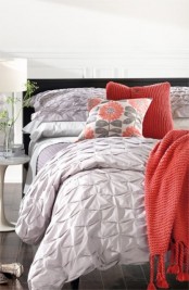 a stylish bedroom with white walls, a grey floor, a black bed, grey, white and coral bedding