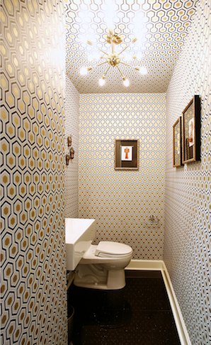A stylish mid century modern toilet with geometric wallpaper, a square sink and a sunburst chandelier