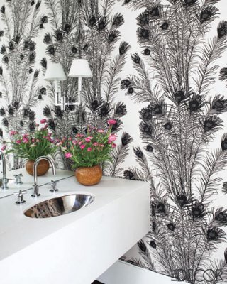 A monochromatic guest toilet with printed wallpaper, a white wall mounted vanity and a lamp