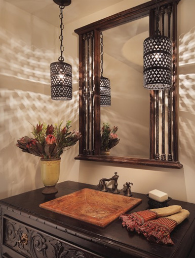 A Moroccan inspired space with hanging lanterns, a mirror in a wooden frame, a dark stained wooden vanity