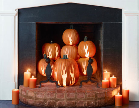 Imitate a real fire with gorgeous stacked carved pumpkins and orange candles.