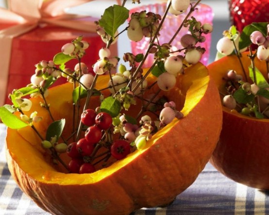 a carved out pumpkin with berries and leaves is a lovely and cool decoration for fall and Thanksgiving