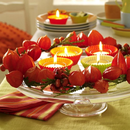 a glass stand with candles, berries and dried blooms is a pretty fall centerpiece of decoration to make