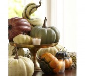 a fall centerpiece of a gold stand with pumpkins, gourds and candles around is a pretty piece to rock in fall or Thanksgiving