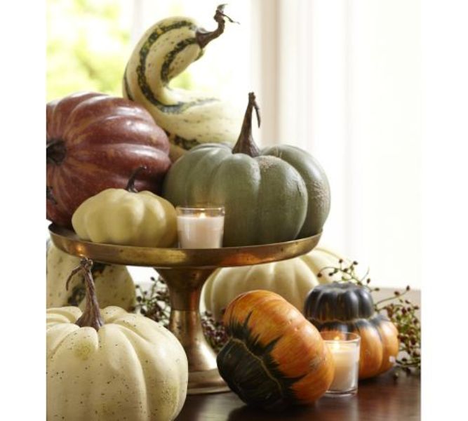 A fall centerpiece of a gold stand with pumpkins, gourds and candles around is a pretty piece to rock in fall or Thanksgiving