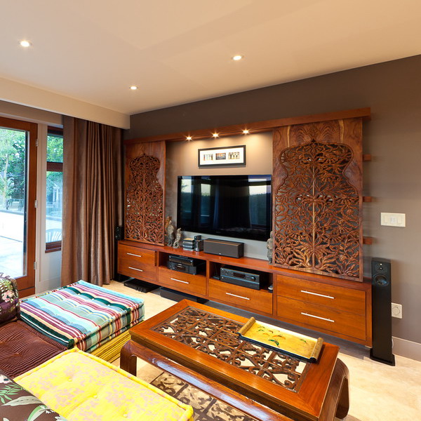A large TV unit and a TV on the wall, with refined laser cut woodne panels that add interest and chic to the space
