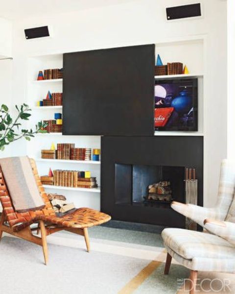 a black fireplace with a TV over it, a matching black panel to hide it and to match the fireplace, such a solution creates a cohesive look