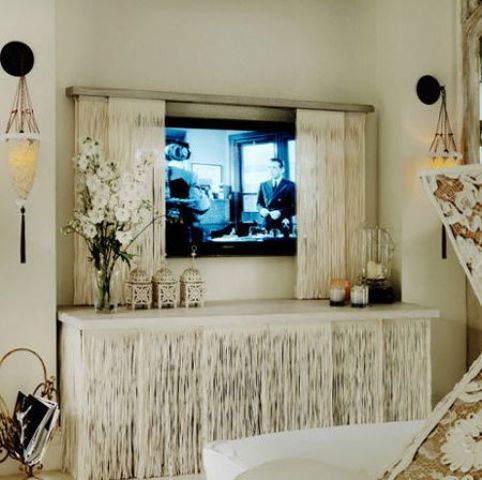 a TV hidden with whitewashed barn doors and with a matching TV unit under it is a cool solution for a boho or rustic space