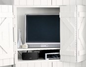 a niche with a TV in the wall, white barn doors covering it and imitating the wall around