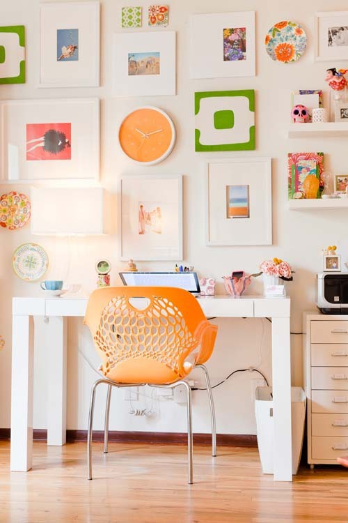 a neutral home office made brighter with some colorful items - an orange chair, bright artwork and books plus some blooms feels inspiring and pretty