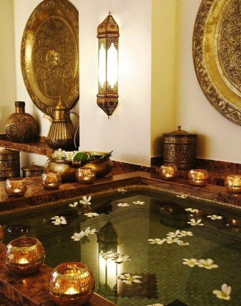 A jaw dropping Asian home space with a large tub or plunge pool clad with tiles, candleholders surrounding the tub, Eastern style lanterns on the wall just wows