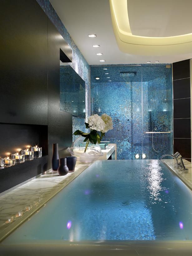 A refined contemporary bathroom with black walls and a white ceiling with built in lights, a shower space clad with blue tiles, a large hot tub is amazing