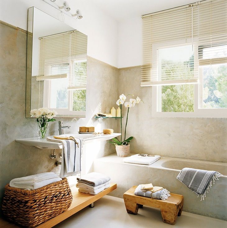 A welcoming neutral home space with a built in bathtub, a floating sink, a mirror cabinet, woodne shelves and a small stool