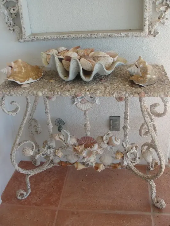 a vintage and elegant console table with seashells - decorated with them and with seashells on it for a coastal feel