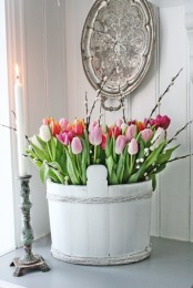 a white wooden bucket with colorful and white tulips plus willow is a beautiful spring decoration or centerpiece