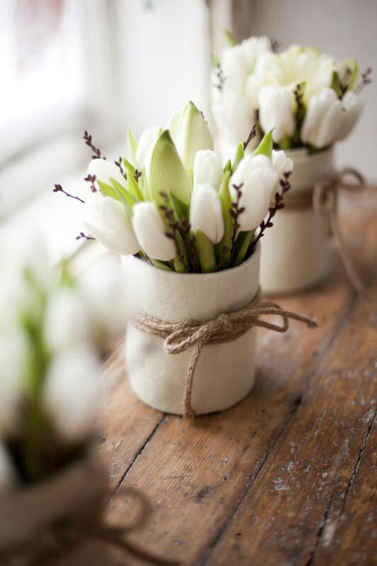 White vases with white tulips, blooms and twine accenting the vases to make them spring like