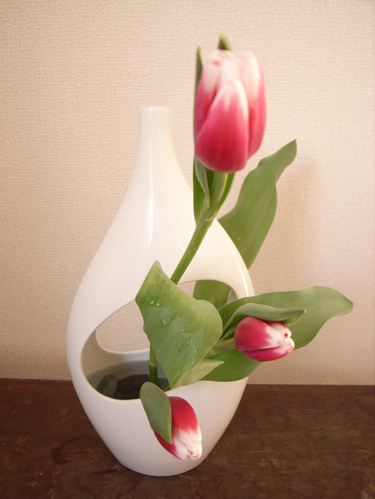 A white cutout back with red to white tulips is a bold ikebana inspried arrangement for spring decor