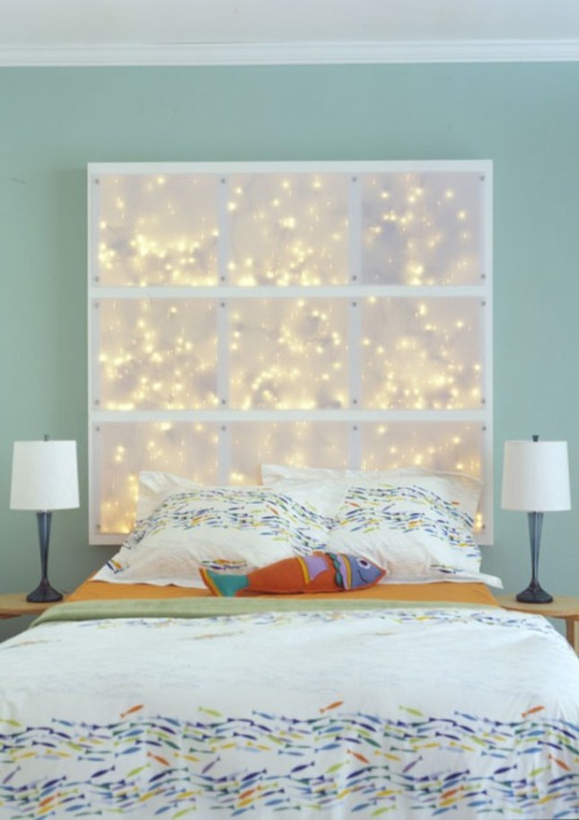 A mint bedroom with a bed and printed bedding, a lit up headboard with string lights and table lamps on both sides